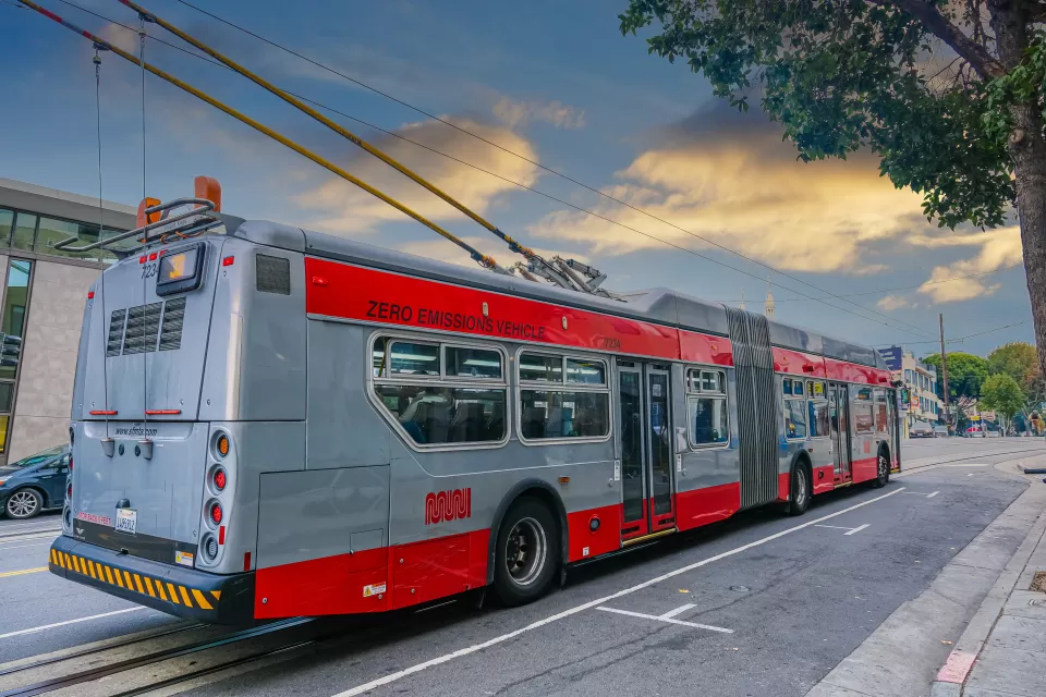 Red and silver Muni trolley bus connected to overhead wires on San Francisco street